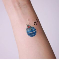 a small christmas ornament with musical notes on it's wrist tattoo design