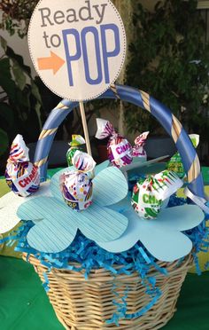 a basket filled with candy sitting on top of a green tablecloth covered table next to a sign