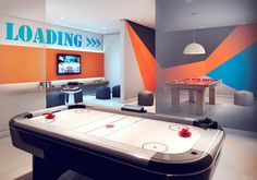 a room with an air hockey table in the center and a tv on behind it