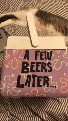 a cat laying on top of a bed next to a pink box that says a few beers later