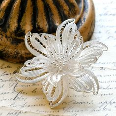 a brooch sitting on top of a piece of paper next to an old book