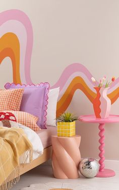 there is a bed with colorful pillows on it and a table next to the bed