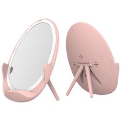 a pink mirror sitting on top of a table next to a wooden stand with legs