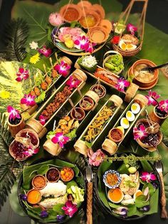 a table topped with lots of different types of food on top of green leafy plates