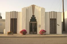 a building with flowers in front of it on the side of the road near a street