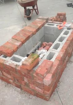 a brick fire pit is being built in the middle of an outdoor area with bricks surrounding it