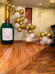 a bottle of champagne sitting on top of a wooden table next to balloons and streamers