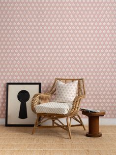 a chair sitting next to a table on top of a hard wood floor in front of a pink wall