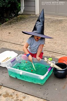 a child in a witches hat playing with green liquid