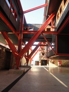 the inside of an empty building with red metal beams on it's sides and floor