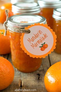 an orange marmalade is in a glass jar on a wooden table surrounded by tangerines