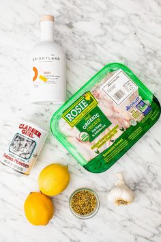 ingredients to make chicken broth laid out on a marble counter top with lemons, garlic and seasoning