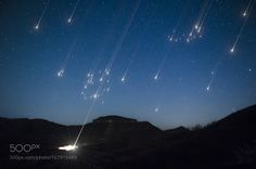 the night sky is filled with stars and bright lights as well as some mountains are in the background