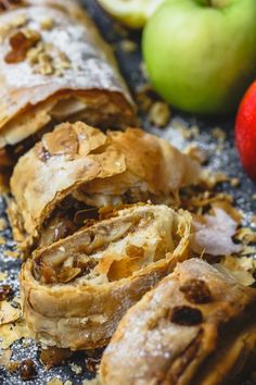 an apple and cinnamon roll cut in half on top of a table with apples behind it