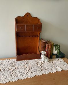 a small teddy bear sitting on top of a table next to a book case and two books