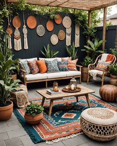 an outdoor living room with lots of potted plants and hanging decorations on the wall