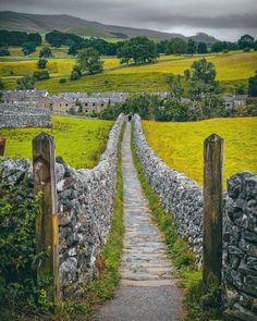 a stone wall and path leading to a green field