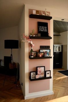 some shelves with pictures and flowers on them in a room that has wood flooring