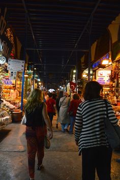 people are walking through an outdoor market at night