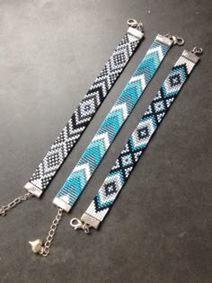 two bracelets with blue and white beaded designs on them, hanging from chains