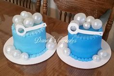 two blue cakes sitting on top of plates covered in white frosting and balloons,