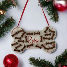 a dog bone ornament hanging from a christmas tree with red ornaments around it