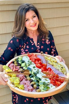 a woman holding a platter full of different types of food