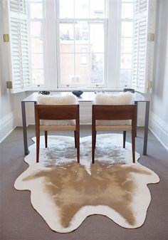 two chairs sitting in front of a table with a cow hide rug on the floor