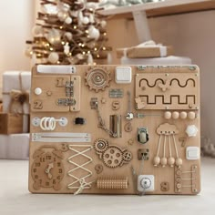 a wooden toy laptop covered in assorted items next to a christmas tree and presents