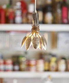 a light hanging from the ceiling in a room with shelves and jars behind it,