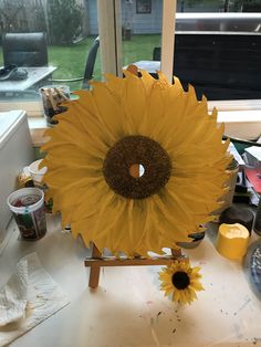 a large sunflower sitting on top of a table next to a painting easel