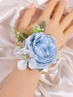 a woman's hand with a blue flower on it and white satin around the wrist