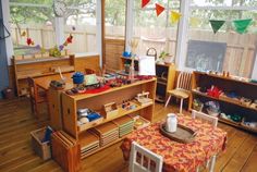 a child's playroom with toys and other items on the table in front of large windows