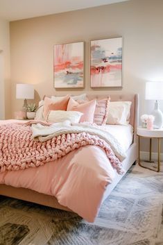 a bed with pink blankets and pillows in a bedroom next to two pictures on the wall