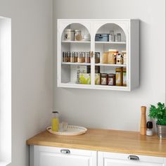 a kitchen with white cupboards and wooden counter top next to a potted plant