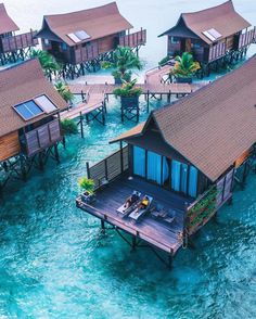 an aerial view of several wooden houses in the ocean with blue water and palm trees