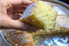 a person holding up a piece of cake in a pan with powdered sugar on top