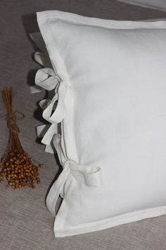 a white pillow sitting on top of a bed next to a dried plant