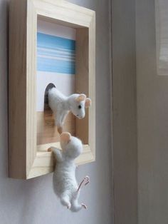 two white mice hanging from a wooden frame