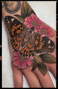 a hand with a butterfly and flowers on it, next to a pocket watch face