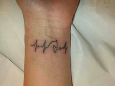 a person with a heartbeat tattoo on their wrist