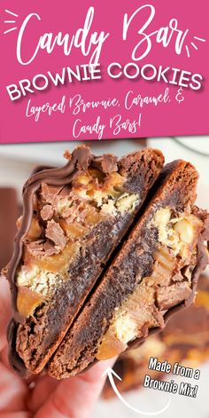 a hand holding up a chocolate cookie with caramel and white chocolate on top, in front of a pink sign that says candy bar brownie cookies