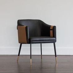 a black chair sitting on top of a hard wood floor next to a white wall