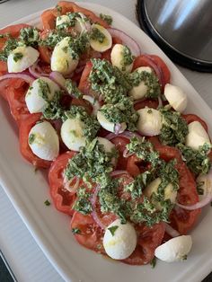 a white plate topped with sliced tomatoes and mozzarella