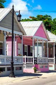 several pink and white houses line the street in front of a lamp post with flowers on it