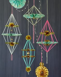 four different colored ornaments hanging from strings on a black wall, with beads and tassels attached to them