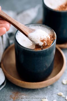 two cups filled with hot chocolate and marshmallows, one being spooned into the cup