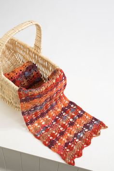 a basket with a scarf hanging from it's side on a counter next to a white wall