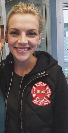 a woman in a chicago fire department jacket posing for a photo with a man wearing a mask behind her