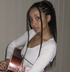 a woman with dreadlocks is holding a guitar and posing for the camera while wearing a white shirt